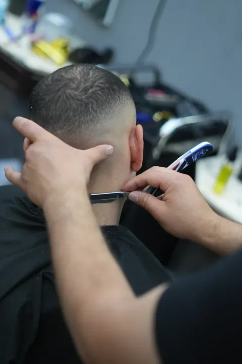 Nahaufnahme eines Haarschneiders am Nacken eines Kunden.