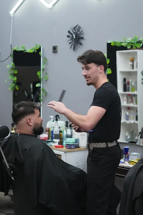 Friseur schneidet einem Kunden am Salonstuhl die Haare.