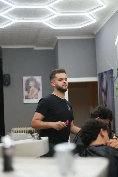 Friseur wäscht einem Gast am Waschbecken die Haare.