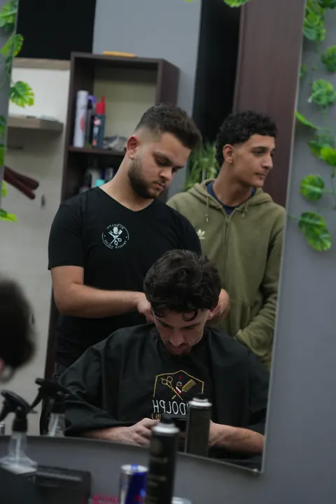 Zwei Friseure arbeiten gleichzeitig an Kunden im Salon.