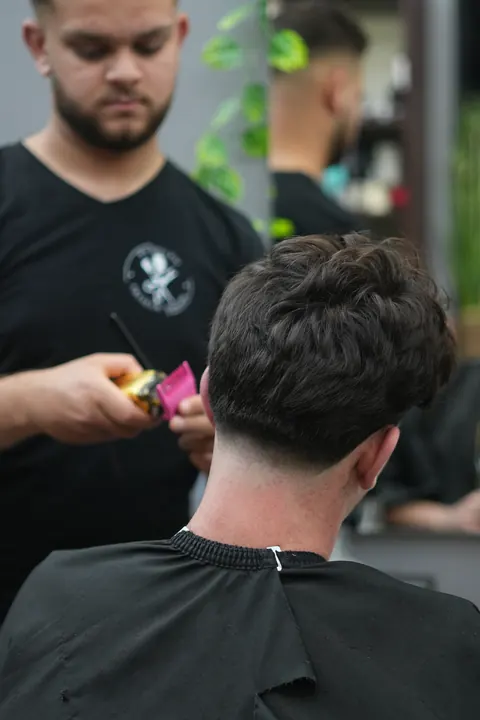 Friseur trägt Stylingprodukt in das Haar ein.